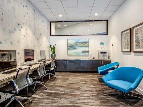 A room with a blue chair and a painting on the wall.