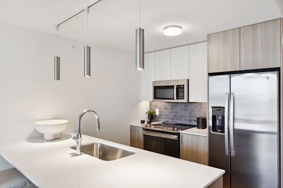 A modern kitchen with a white countertop and stainless steel appliances.