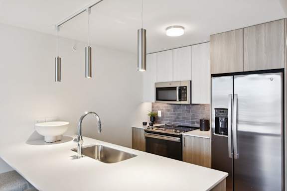 A modern kitchen with a white countertop and stainless steel appliances.