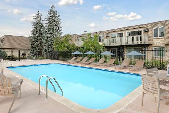 Pool deck with lounge chairs and umbrellas at Cedarvale Highlands Apartments, Eagan, MN