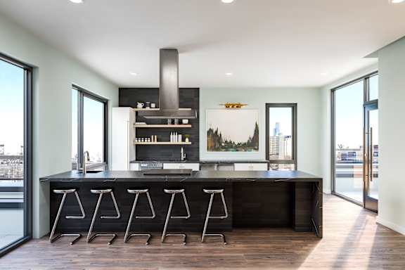 A modern kitchen with a large island and stools.