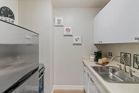 A kitchen with a stainless steel refrigerator and white cabinets.