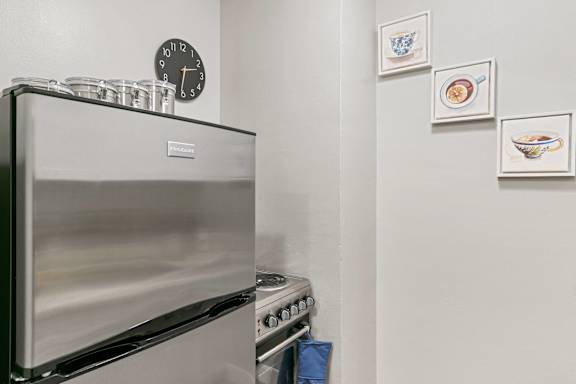 A stainless steel oven with a clock above it and three pictures on the wall.