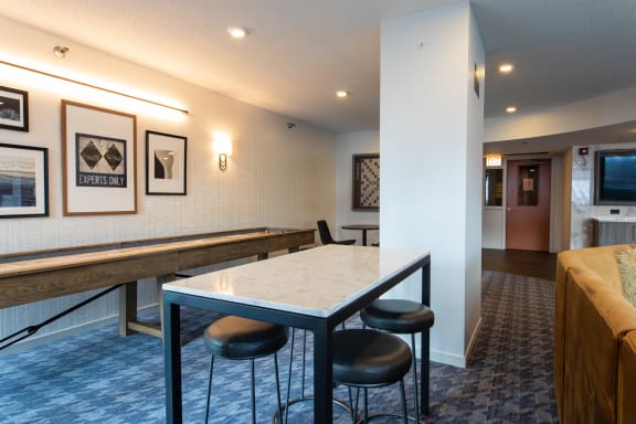 a table with four stools in a room with a sofa and a television at Kingsbury Plaza, Chicago, IL, 60654