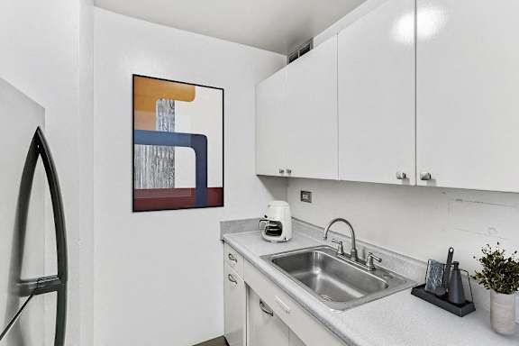 A modern kitchen with a sink, a toaster, and a painting on the wall.