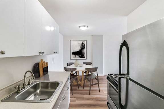 A modern kitchen with a stainless steel refrigerator and a dining table set for two.