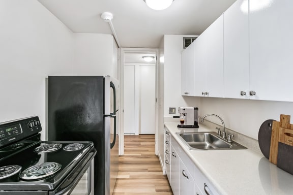 a kitchen with white cabinets and black appliances at The Pavilion, Detroit, MI, 48207