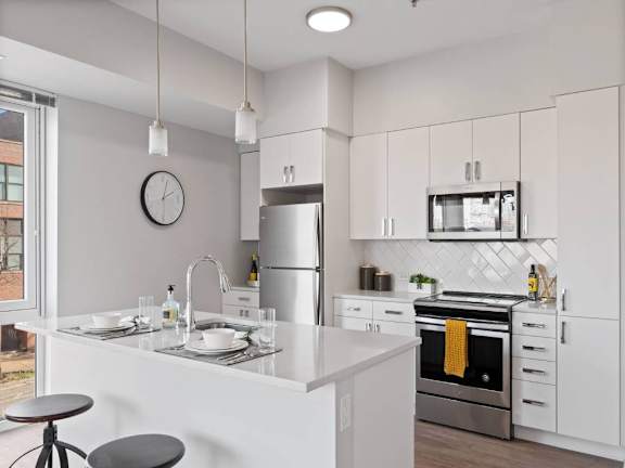 A modern kitchen with a white countertop and stainless steel appliances.