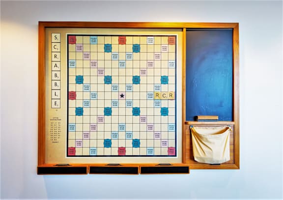 A Scrabble board with letters on it and a bag of tissues next to it.