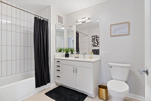 a bathroom with a white toilet and a black shower curtain