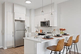 a kitchen with a white counter top and a stainless steel refrigerator