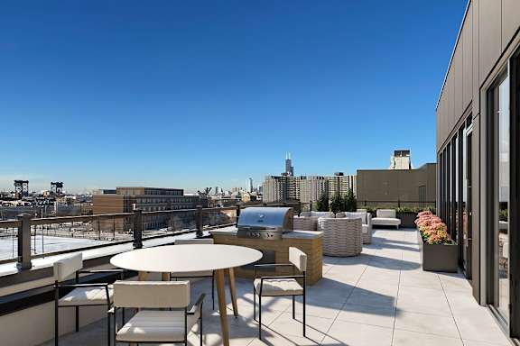 a terrace with a table and chairs and a grill on top of a building