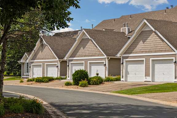 A row of houses with garages and a tree on the left at Seasons Villas, Woodbury, MN 55125
