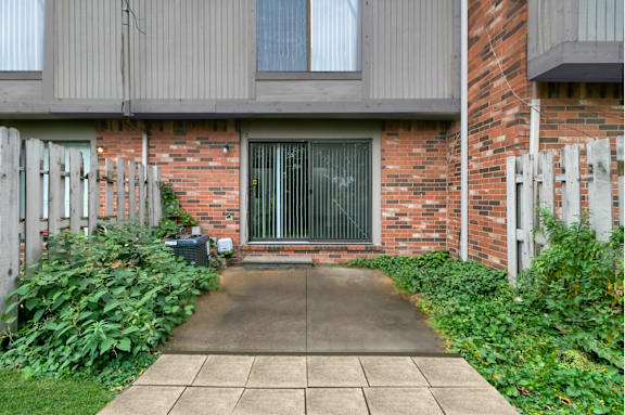 A brick building with a grey door and a concrete walkway leading to it at The Village of Hyde Park, Detroit, MI