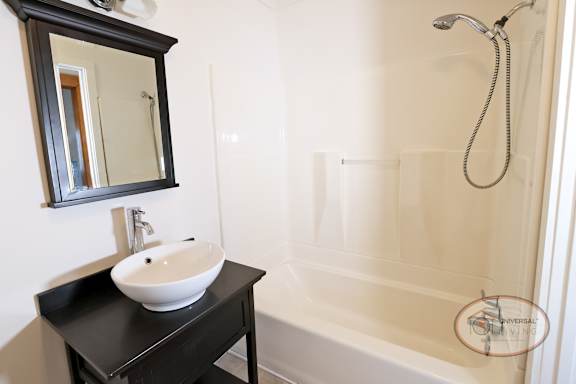 A bathroom with a sink, mirror, and shower over tub.