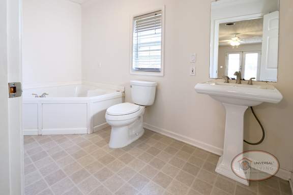 The master bathroom with sink, toilet, and large tub.