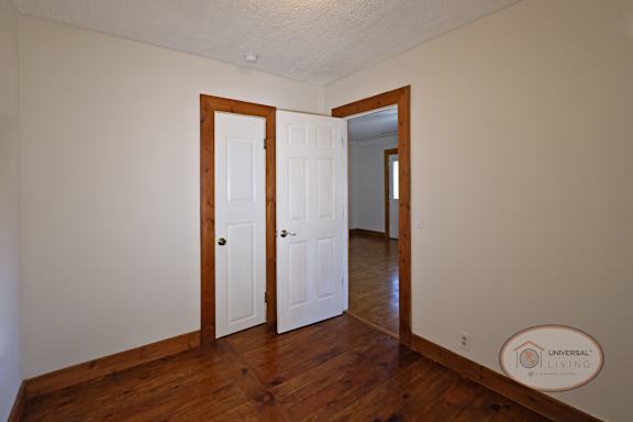 A spare room off of the living room with hardwood flooring.