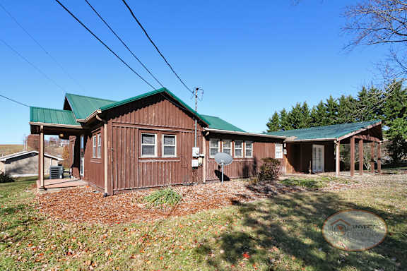 The side of a rustic cabin style two bedroom home with a green roof.