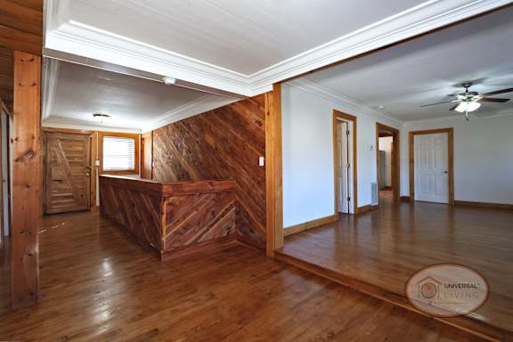 The foyer of a two bedroom two bath home with wooden accents, stairs leading into the basement, and living room.