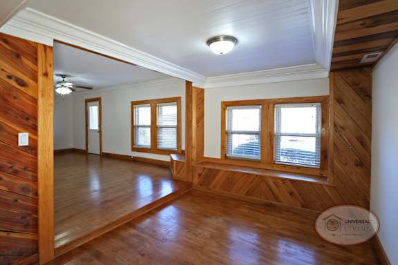 The foyer of a two bedroom two bath home with wooden accents, stairs leading into the basement, and living room.