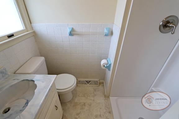 A bathroom with toilet, sink, and shower.