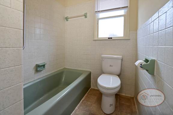 A white toilet sits next to a green bathtub.