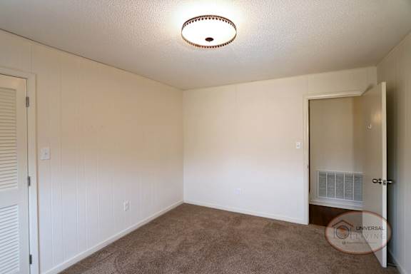 A bedroom with carpet and white walls.