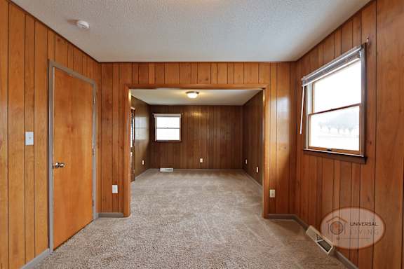 A bedroom with wood paneling, carpet, and room divider.
