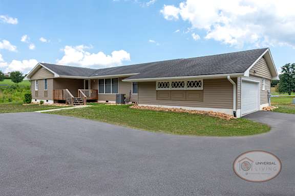 A tan house with dark roof, paved driveway and garage.