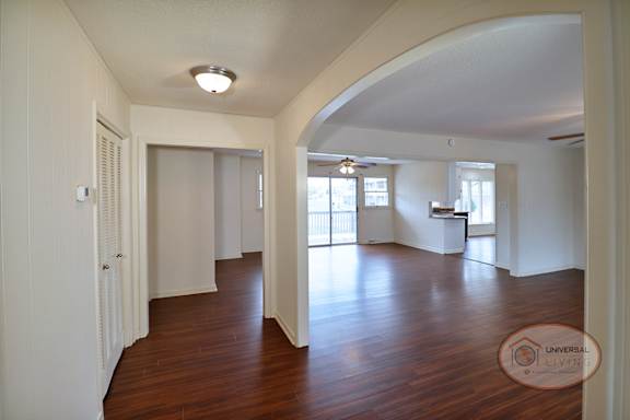 A spacious living room with wood flooring and white walls.