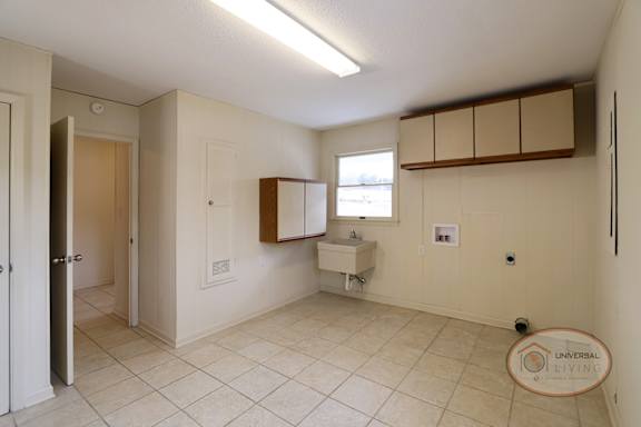 The laundry room with tile, white walls, and cabinets.