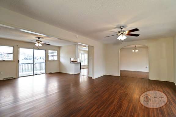 A spacious room with hardwood floors, glass patio doors, and ceiling fan.