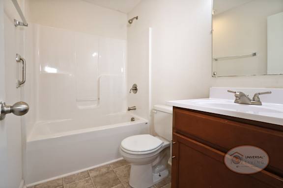 A bathroom with tub and shower, toilet, sink and dark cabinets.