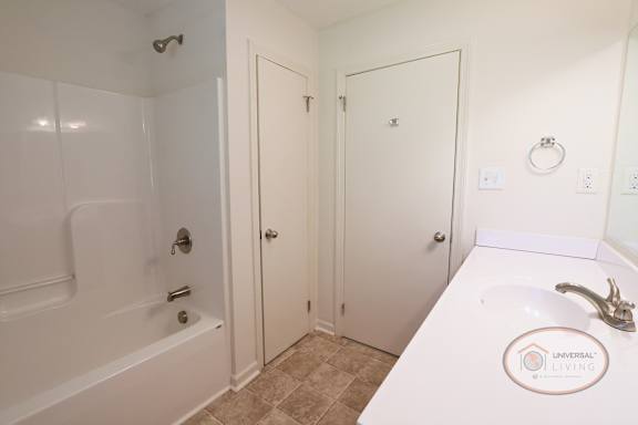 A bathroom with a tub, sink and closet.