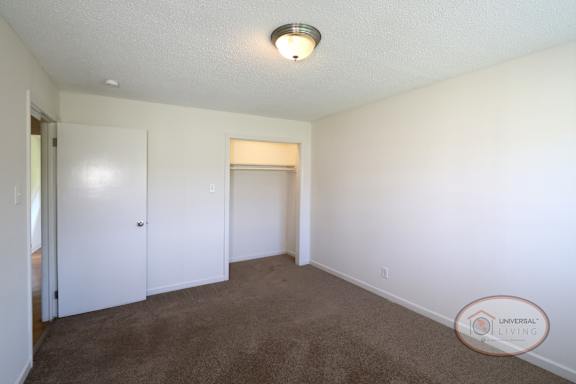 A bedroom with carpet, a closet, and white walls.