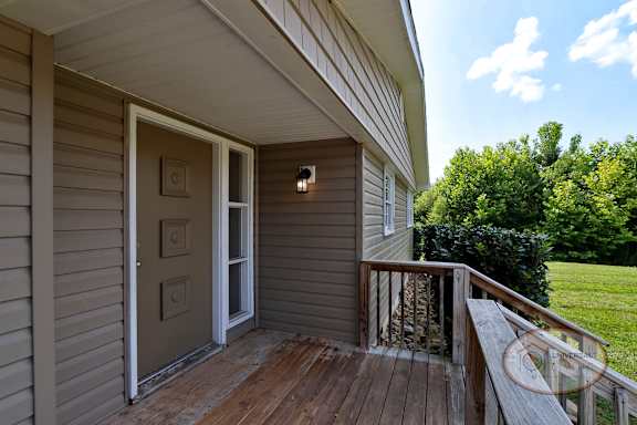 The porch of a house with a tan door.