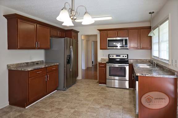 A kitchen with brown wooden  cabinets, stainless steel appliances, and tile floor.