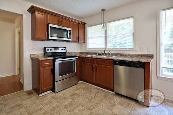 A kitchen with brown wooden cabinets and a granite style countertop.