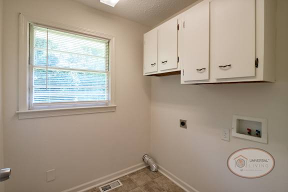 The laundry room with cabinets, vinyl floor, and window.