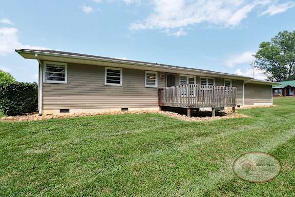 The rear of a grey home with a back deck.