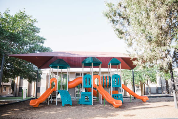 Colorful playground equipment under shade canopy at Cantera Apartments, El Paso, 79935
