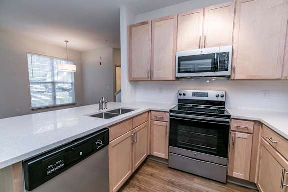 A kitchen with wooden cabinets and a black dishwasher at 1701 North Apartment Homes Apartments, North Carolina