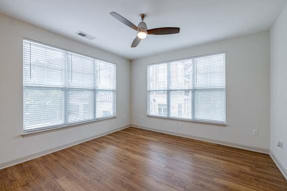 A room with a ceiling fan and two windows. at 1701 North Apartment Homes Apartments, Chapel Hill, NC