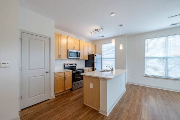 A kitchen with wooden cabinets and a white island. at 1701 North Apartment Homes Apartments, Chapel Hill, NC