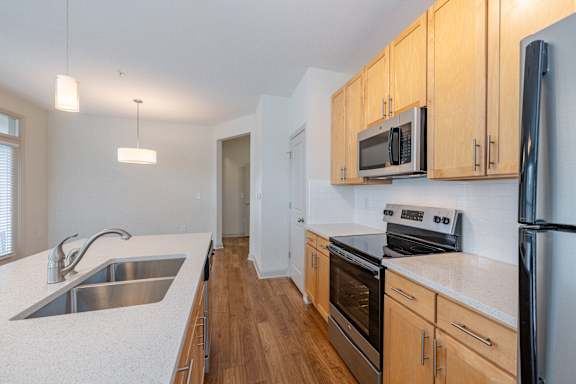 Kitchen with wooden cabinets and appliances at 1701 North Apartment Homes Apartments, North Carolina, 27514