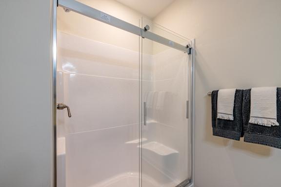 A white bathroom with a glass shower door and a white tub at 1701 North Apartment Homes Apartments, Chapel Hill, North Carolina