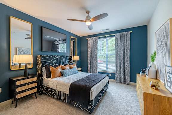 A bedroom with a bed, dresser, and mirror at 1701 North Apartment Homes Apartments, Chapel Hill, 27514