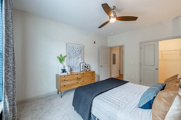 A bedroom with a bed, dresser, and ceiling fan and light at 1701 North Apartment Homes Apartments, Chapel Hill