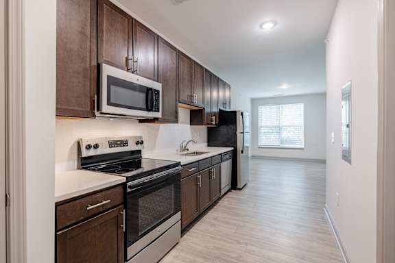 A kitchen with dark wood cabinets and stainless steel appliances at 1701 North Apartment Homes Apartments, Chapel Hill, NC