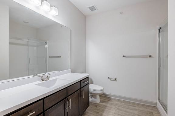 A white bathroom with a sink, toilet, and mirror at 1701 North Apartment Homes Apartments, North Carolina, 27514